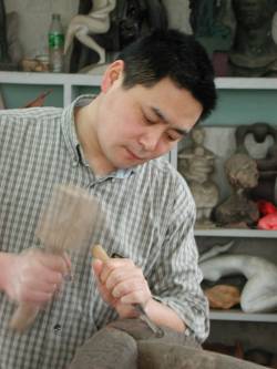 Shen Xiaonan working on a wood sculpture in his rooftop studio